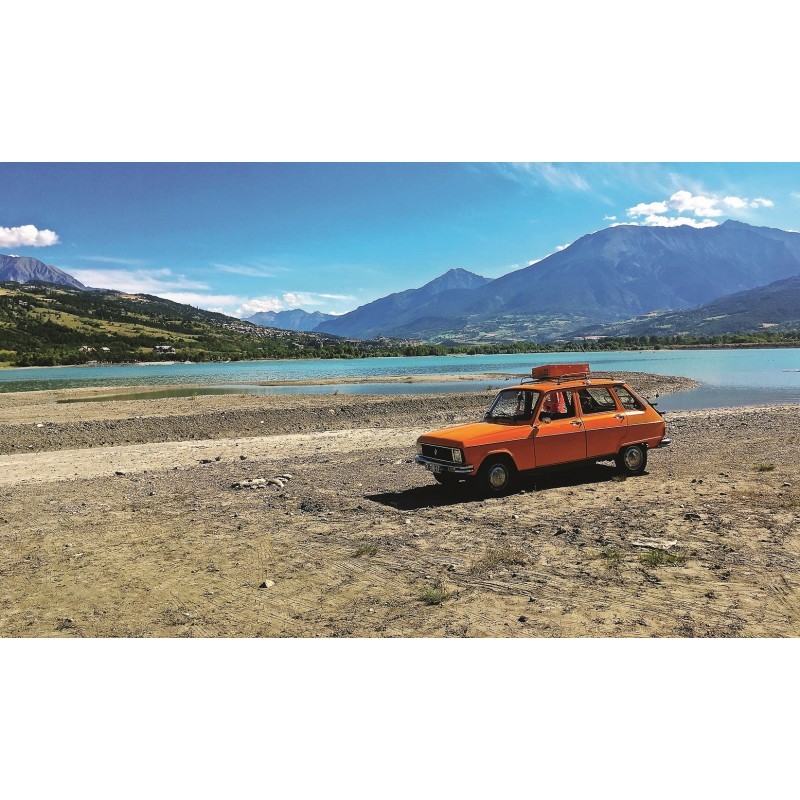 La Renault 6 de Mon Père Carro clássico laranja junto a lago e montanhas sob céu azul