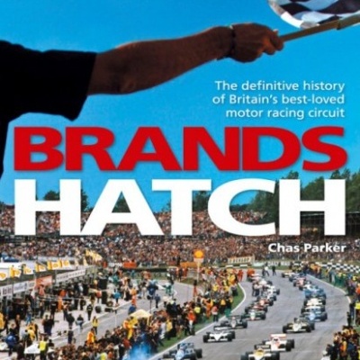 Capa de livro com título BRAHDS HATCH, mão a acenar bandeira xadrez e corrida de carros de motor
