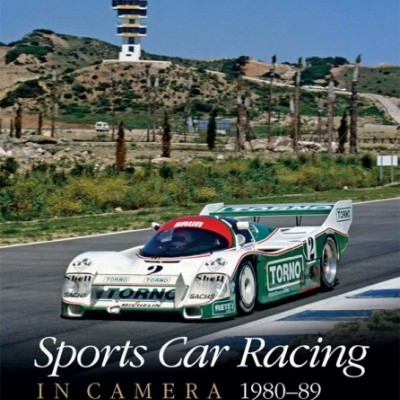 Capa de livro com carro de corrida branco, verde e vermelho na pista e torre ao fundo