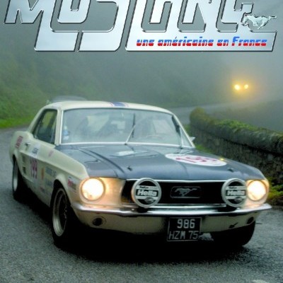 Ford Mustang clássico branco e preto com faróis ligados em estrada nevoenta