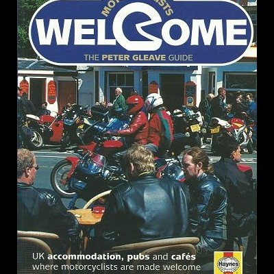 Capa de guia para motociclistas com letreiro azul e branco e pessoas com casacos de couro perto de motos