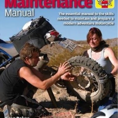 Capa de livro com duas pessoas a ajustar roda traseira de mota de aventura em ambiente seco