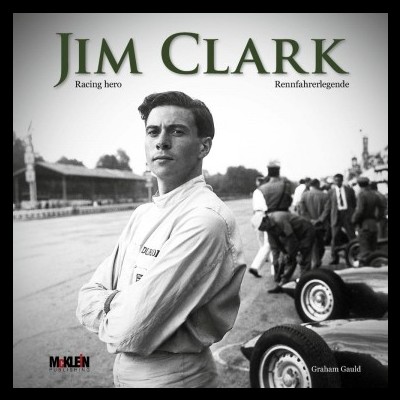 Jim Clark com fato de corrida branco em pista de carros clássicos, pessoas ao fundo