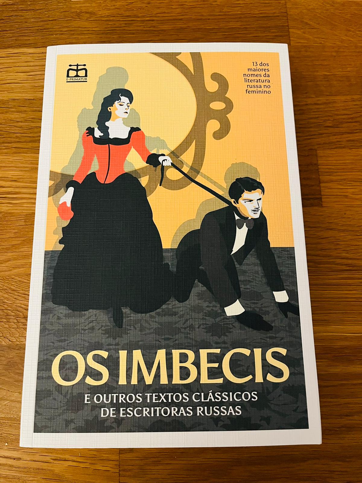 Os Imbecis e Outros Textos Clássicos de Escritoras Russas Livro com capa ilustrada mostrando mulher com vestido vermelho a segurar trela amarrada a homem com roupa preta