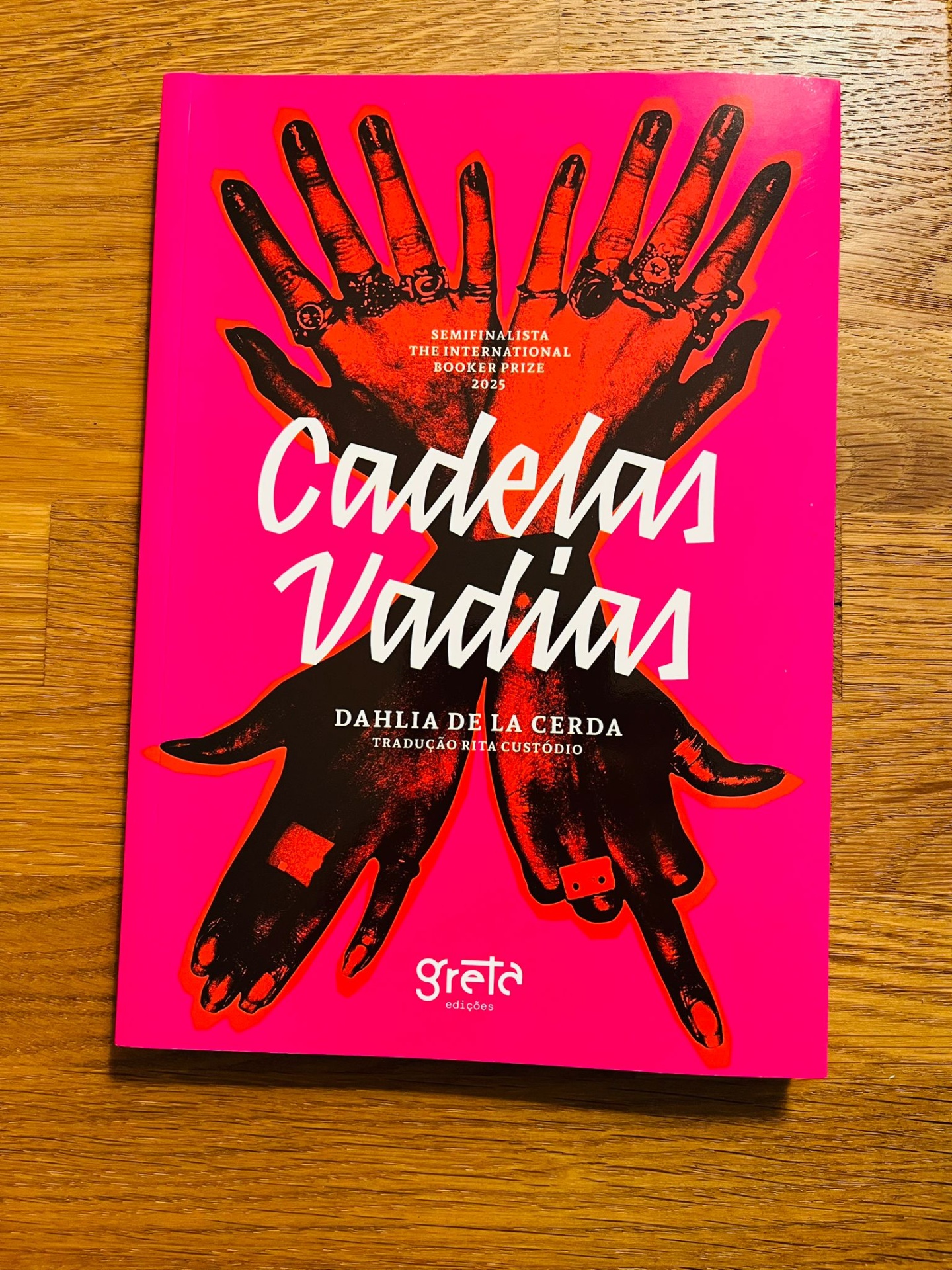 Cadelas Vadias, de Dahlia de la Cerda Capa de livro rosa com mãos negras cruzadas e texto em branco Cadeias Vadias