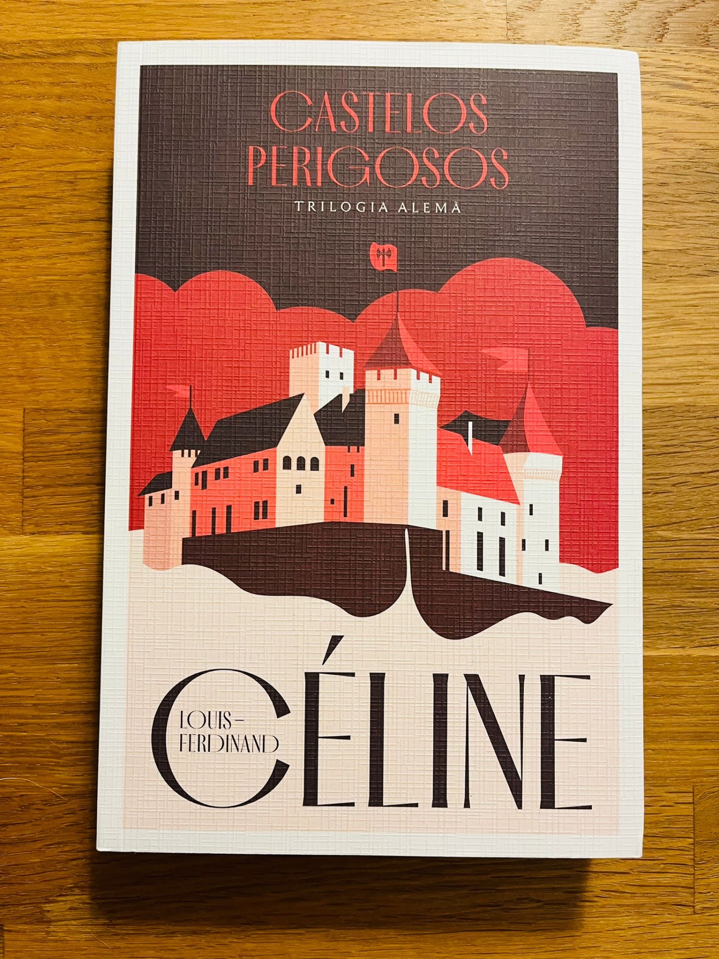 Castelos Perigosos - Trilogia Alemã I, de Louis-Ferdinand Céline Capa de livro com castelo ilustrado em vermelho, branco e preto e texto 'CASTELOS PERIGOSOS TRILOGIA ALEMÃ' e 'LOUIS-FERDINAND CÉLINE'.