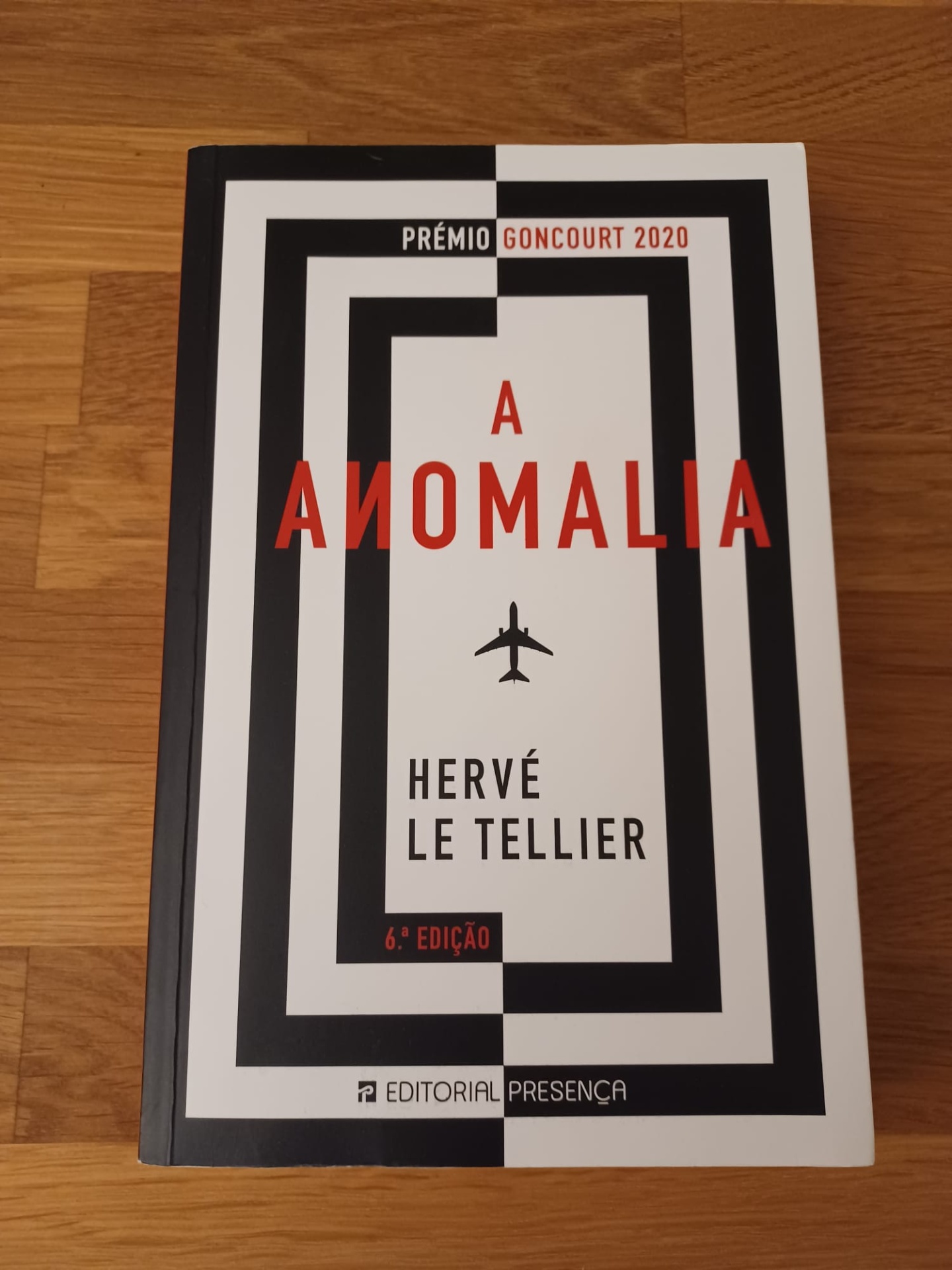 A Anomalia, de Hervé Le Tellier Capa do livro A Anomalia de Hervé Le Tellier com texto em preto e vermelho sobre fundo branco e preto