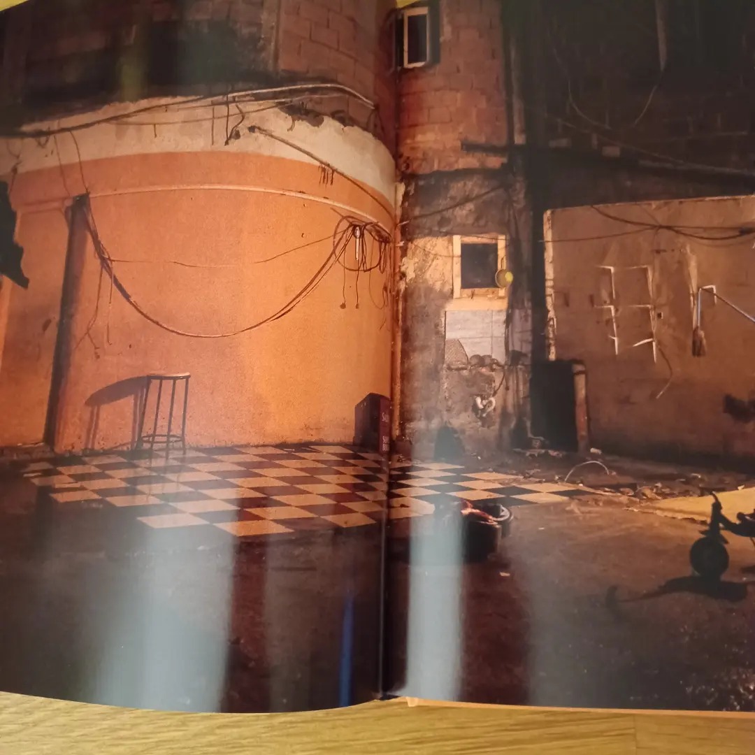 Jamaika, de José Sarmento Matos Espaço interior com paredes envelhecidas, chão de azulejos em padrão quadriculado e pequena mesa de metal