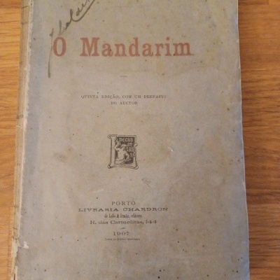 Livro antigo 'O Mandarim' com capa azul esbatida e manchas, edição de 1907.