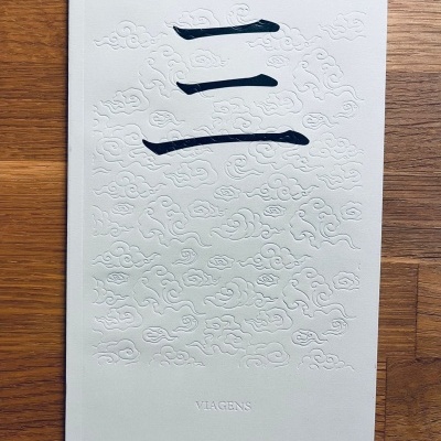 Capa branca texturizada de livro com padrões em relevo e texto VIAGENS