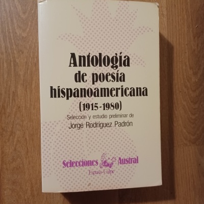 Livro Antología de poesía hispanoamericana sobre mesa de madeira