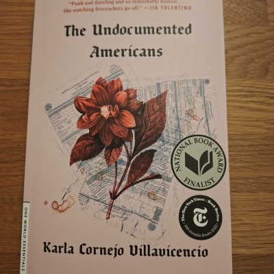 Capa do livro The Undocumented Americans com flor vermelha e selos de prémios em fundo branco.
