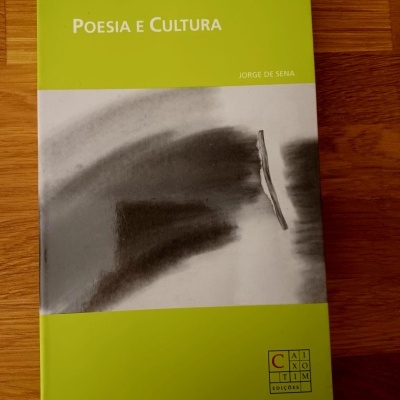 Livro POESIA E CULTURA de cor verde e branca com imagem abstrata preto e branco, sobre superfície de madeira.