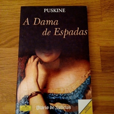 Livro 'A Dama de Espadas' de Puskine com capa retrato de mulher e etiqueta 'EDIÇÃO INTEGRAL'