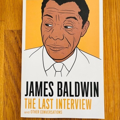 Livro James Baldwin The Last Interview com capa ilustrada e chão de madeira