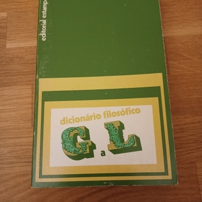Livro dicionário filosófico G a L com capa verde, branco e amarelo sobre mesa de madeira clara