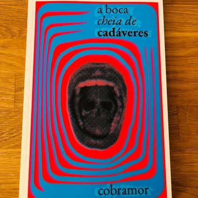 Capa de livro azul com detalhes vermelhos e texto a boca cheia de cadáveres cobramor