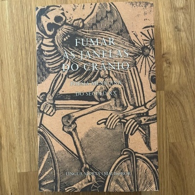 Capa de livro castanha com esqueletos a andar de bicicleta e texto em branco