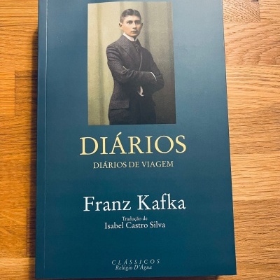 Capa de livro 'Diários' de Franz Kafka com fotografia de homem jovem em fundo azul escuro