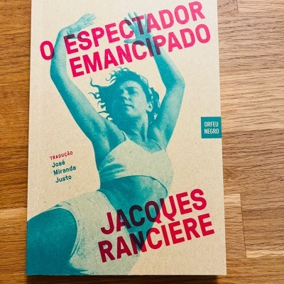 Livro O Espectador Emancipado de Jacques Ranciere com capa bege e imagem azul de mulher