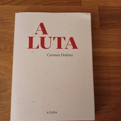 Livro branco com título vermelho e texto preto sobre madeira clara