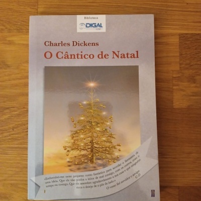 Capa de livro 'O Cântico de Natal' de Charles Dickens com árvore de Natal dourada iluminada