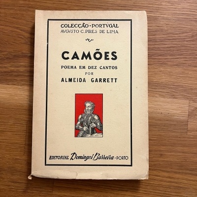 Capa de livro antigo Camões com desenho e texto em português.