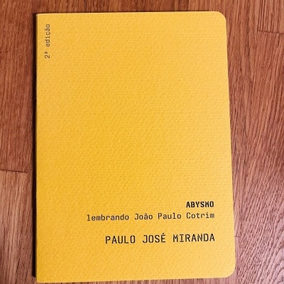 Livro amarelo com texto impresso sobre superfície de madeira.