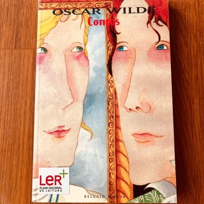 Capa do livro 'Oscar Wilde Contos' com ilustração de dois rostos e selo LER+