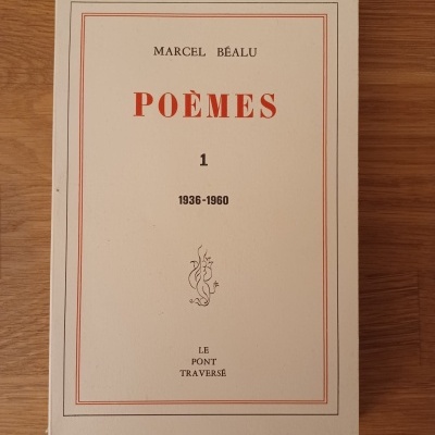 Capa branca de livro POÈMES 1 de Marcel Béalu com texto em vermelho e preto sobre mesa de madeira clara