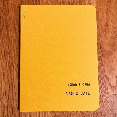 Capa amarela de livro 'VIRAR A CARA VASCO GATO' em superfície de madeira.