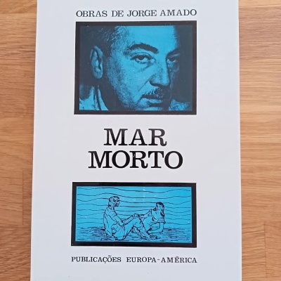 Livro 'Mar Morto' de Jorge Amado com capas branca e azul sobre uma mesa de madeira