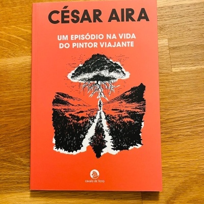 Livro vermelho com título e ilustração em preto e branco numa superfície de madeira