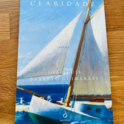 Livro com capa ilustrada por pintura de veleiro em mar azul com céu claro