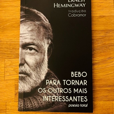 Capa preta de livro com foto a preto e branco de rosto masculino e texto de Ernest Hemingway