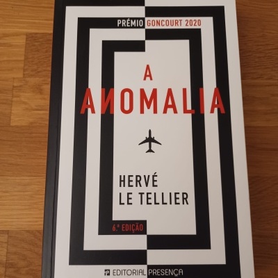 Capa do livro A Anomalia de Hervé Le Tellier com texto em preto e vermelho sobre fundo branco e preto