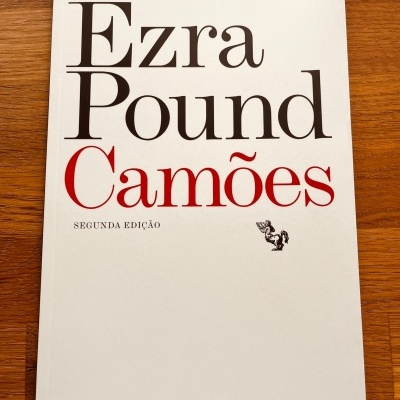 Capa branca de livro 'Ezra Pound Camões' com texto preto e vermelho sobre madeira