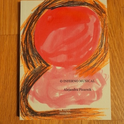 Livro O INFERNO MUSICAL de Alejandra Pizarnik com capa colorida em cima de chão de madeira