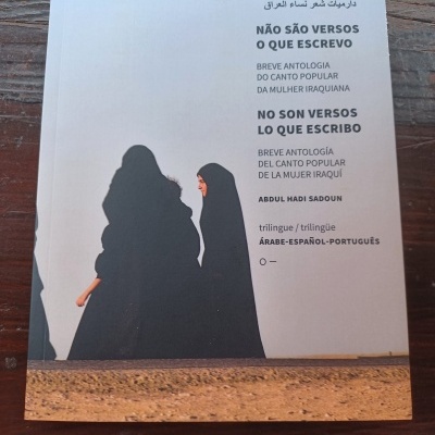 Livro trilíngue com capa branca e duas mulheres vestidas de negro na imagem