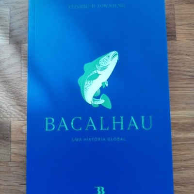 Livro azul com ilustração de peixe e título Bacalhau numa superfície de madeira