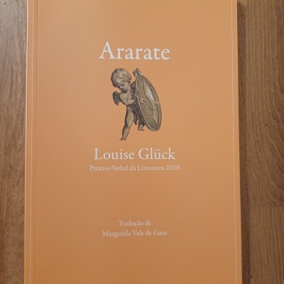 Livro 'Ararate' de Louise Glück com capa laranja e figura segurando escudo