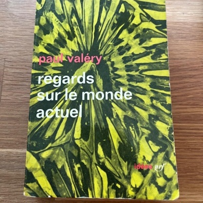Capa de livro verde e amarelo com texto em francês sobre mesa de madeira