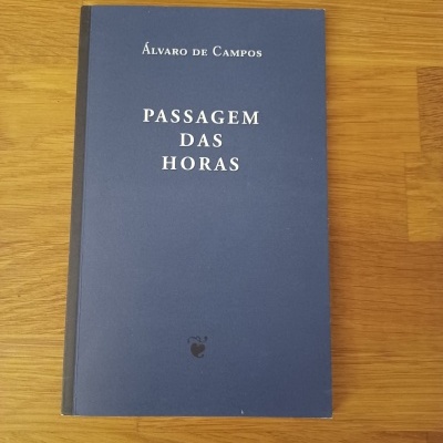 Livro 'Passagem das Horas' de Álvaro de Campos com capa azul e lombada preta em superfície de madeira.