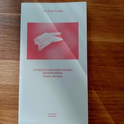 Livro 'A POESIA É UMA MERCADORIA INCONSUMÍVEL' de Pier Paolo Pasolini numa mesa de madeira