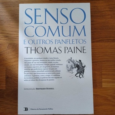 Livro 'Senso Comum e Outros Panfletos' de Thomas Paine sobre mesa de madeira