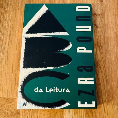 Livro verde escuro com texto e gráficos em preto e branco sobre superfície de madeira