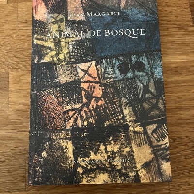 Livro Animal de Bosque de Joan Margarit com capa em tons de castanho e azul sobre madeira