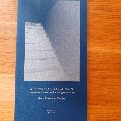Livro azul com fotografia de escada e texto branco na capa sobre superfície de madeira