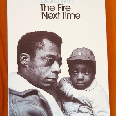 Capa de livro 'The Fire Next Time' de James Baldwin com foto a preto e branco de homem e criança