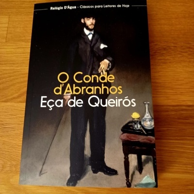 Livro 'O Conde d'Abranhos' de Eça de Queirós com capa preta e imagem de homem vestido de fato escuro